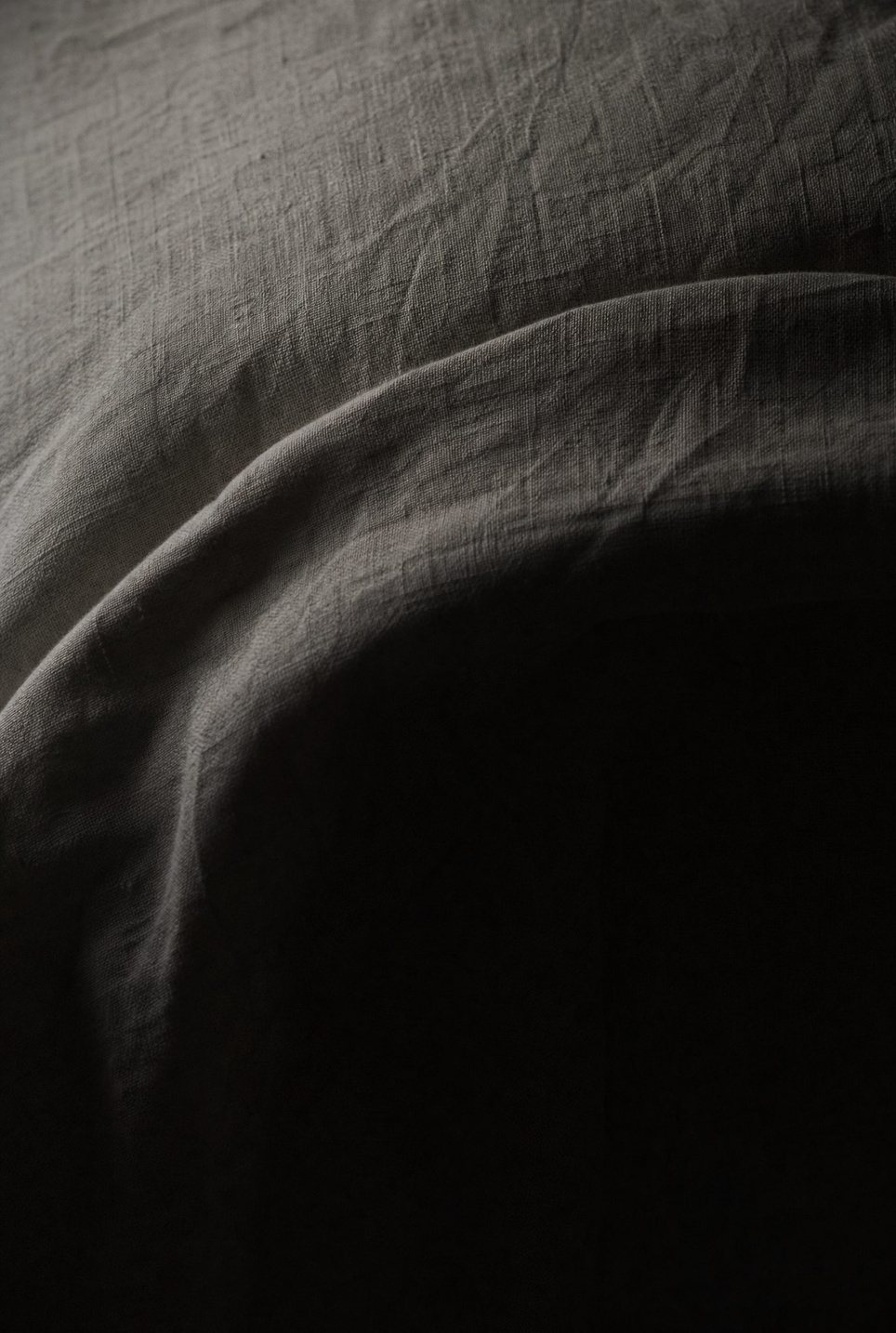 Softly draped bed linen in warm shadow light